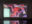 Video installation by Lu Bassett showing layered abstract digital forms in pink, red, black and pale green on a wall-mounted screen.