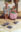 Narrative painting by Jamie Morris showing an older woman and young girl eating ice cream on a porch while pigeons gather nearby.