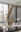 bronze sculpture resembling a curled organic form suspended by a hook against a blurred studio background.