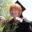 Portrait of multidisciplinary artist Rayna Johnson-Menard smiling outdoors at a graduation ceremony while holding a bouquet of flowers.