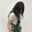Portrait of artist Halle Lim wearing a soft, textured wearable sculpture made of blue-green fibre with living plants woven throughout the piece.