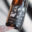 Craft beer bottle featuring black label artwork with illustrated birds, a dog, and a musician in a whimsical line-drawn style.
