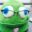 Whimsical green felt creature with large blue-and-white eyes and freckles, wearing black-framed eyeglasses.