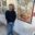 Portrait of landscape painter Peter Buwalda standing beside one of his large-scale paintings in an art gallery.