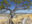 Panoramic landscape painting of a windswept juniper overlooking rolling grasslands, a winding river valley, and distant mountain peaks beneath a deep blue sky.