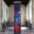 Monumental multi-panel figurative painting installed in a medieval church gallery depicting an abstract human form in flowing red, blue, and violet tones.