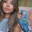 Portrait of artist Rachel Rivera holding a paintbrush in front of a colourful parrot painting.