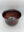 Close-up view of a dark engraved glass vessel with swirling decorative patterns etched into its surface.