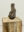 Organic wood sculpture displayed on a rustic reclaimed wooden pedestal in a gallery space.