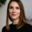 Professional portrait of Shannon Hewlko smiling at the camera while wearing a black sweater in a bright studio setting.