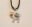 Sterling silver bison-shaped pendant by Karen Kryzan featuring buffalo turquoise and carnelian stones, suspended from a dark silk cord.