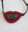Pendant by Karen Kryzan featuring a dark snowflake obsidian stone set within a sculptural red acrylic form resembling lips, suspended from a black cord.